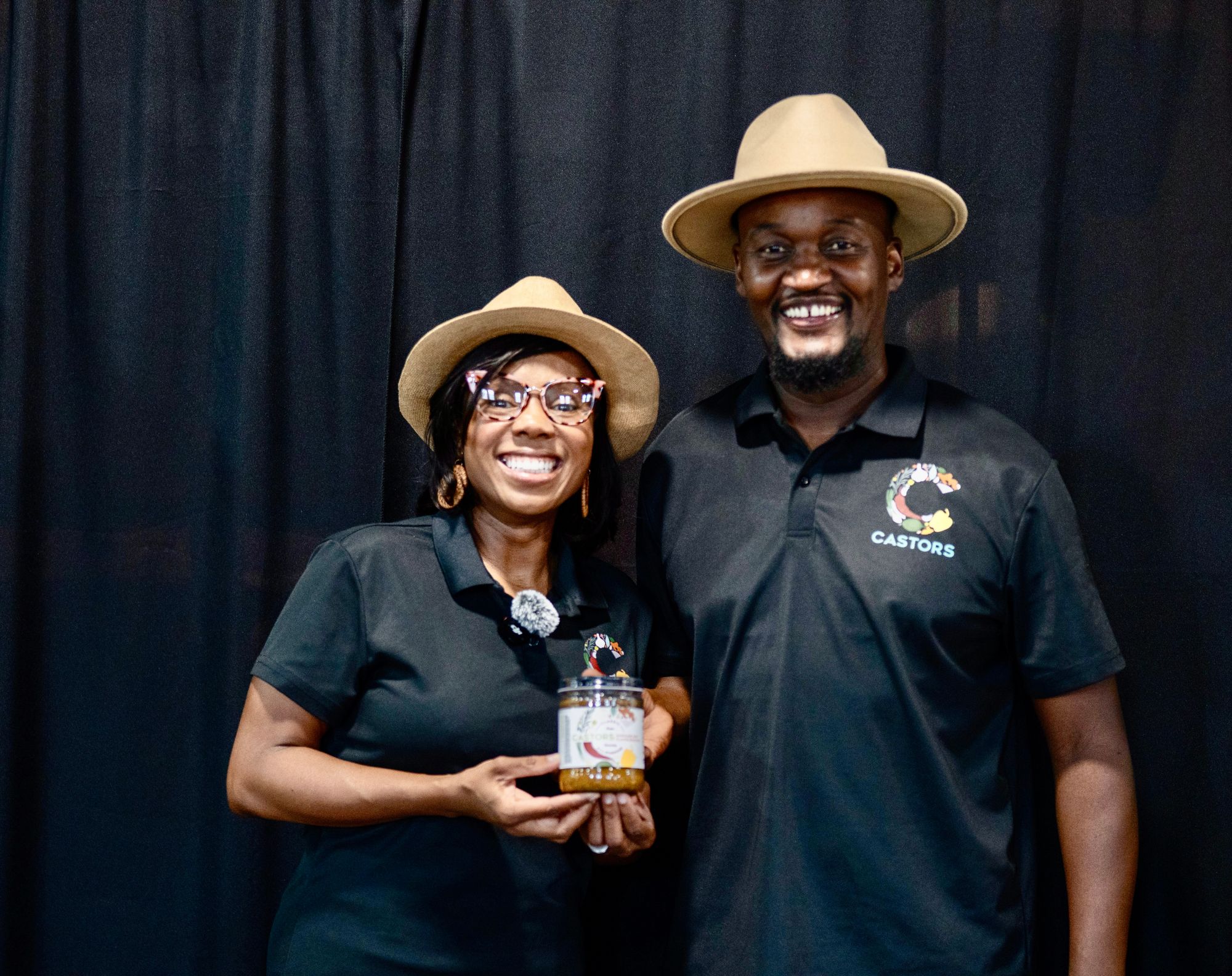 Two CASTORS team members smiling together holding a jar of seasoning