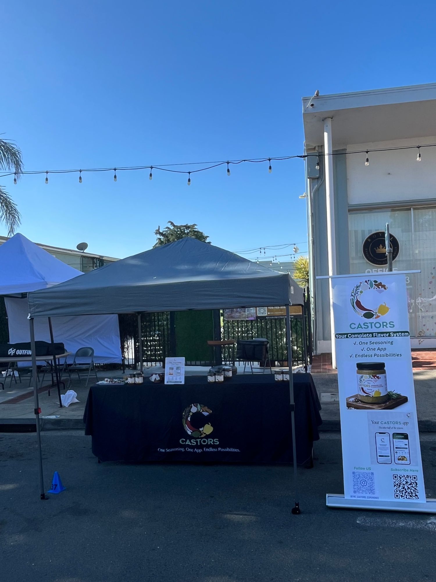 CASTORS outdoor market booth setup under a canopy with branded signage and products on display
